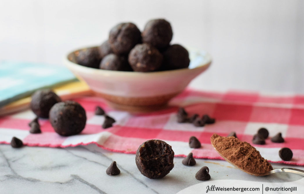 healthy chocolate walnut date balls with chocolate chips and a spoonful of cocoa powder