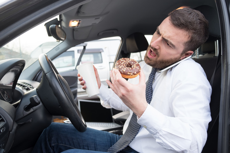 man eats a donut in the car