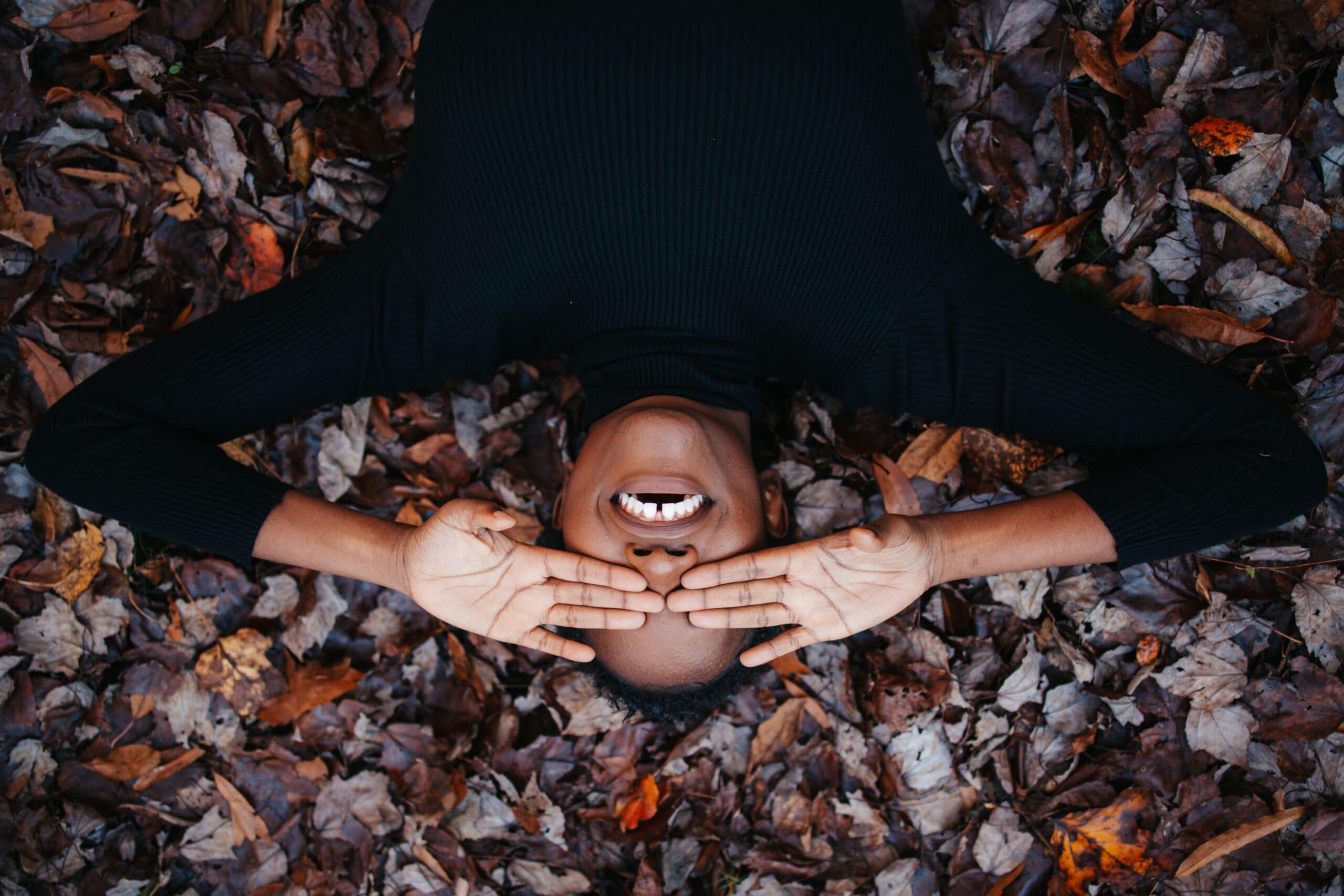 Relieved woman lying on a bed of fall leaves